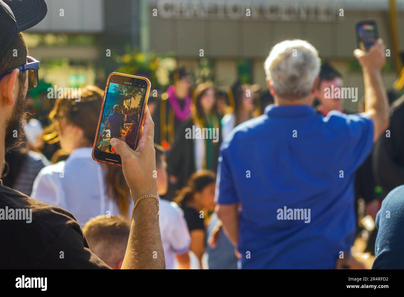 Une image montrant une personne capturant le moment de la classe de 2023 Crafton Hills College marchant au début du commencement par un téléphone, Banque D'Images