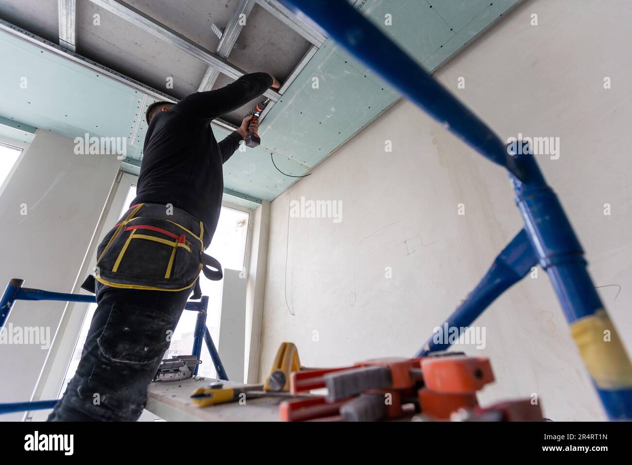 Installation au plafond avec des techniciens experts dans la salle en cours de construction. Banque D'Images