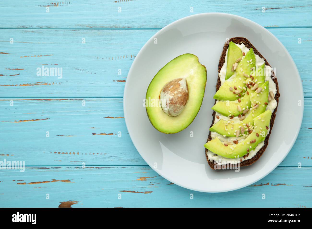 Sandwich à l'avocat sur du pain de seigle foncé fait avec la moitié de l'avocat sur fond bleu. Vue de dessus Banque D'Images