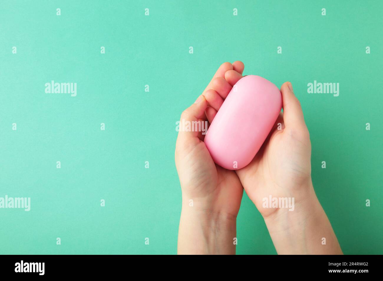 Femme main tenant une barre de savon rose sur un fond de menthe. Vue de dessus Banque D'Images