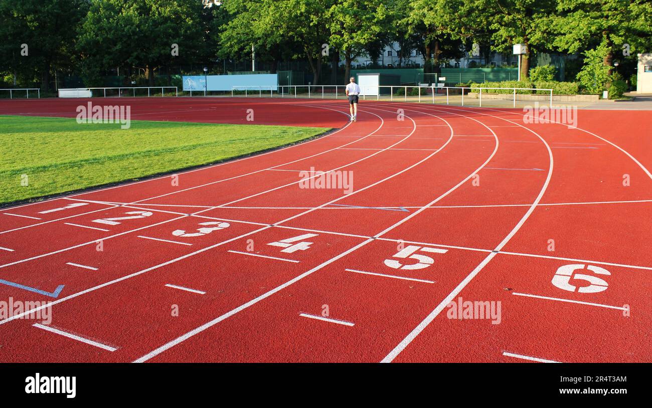 Piste de course rouge avec lignes blanches dans un stade de sport en plein air. Banque D'Images