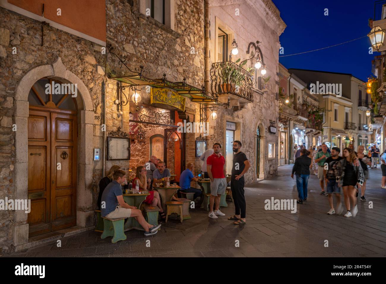 Vue sur les cafés et les restaurants dans la rue animée de Taormina au crépuscule, Taormina, Sicile, Italie, Europe Banque D'Images