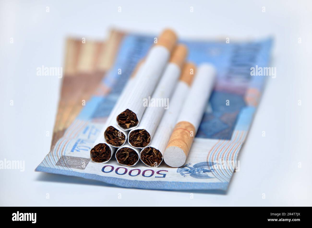 Cigarette avec l'argent indonésien sur fond blanc studio de tournage Banque D'Images