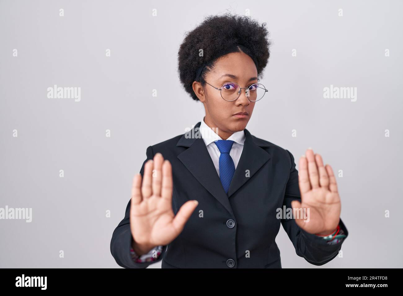 Belle femme africaine aux cheveux bouclés portant une veste d'affaires et des lunettes se déplaçant les mains paumes montrant le refus et le déni avec peur et dégoût Banque D'Images