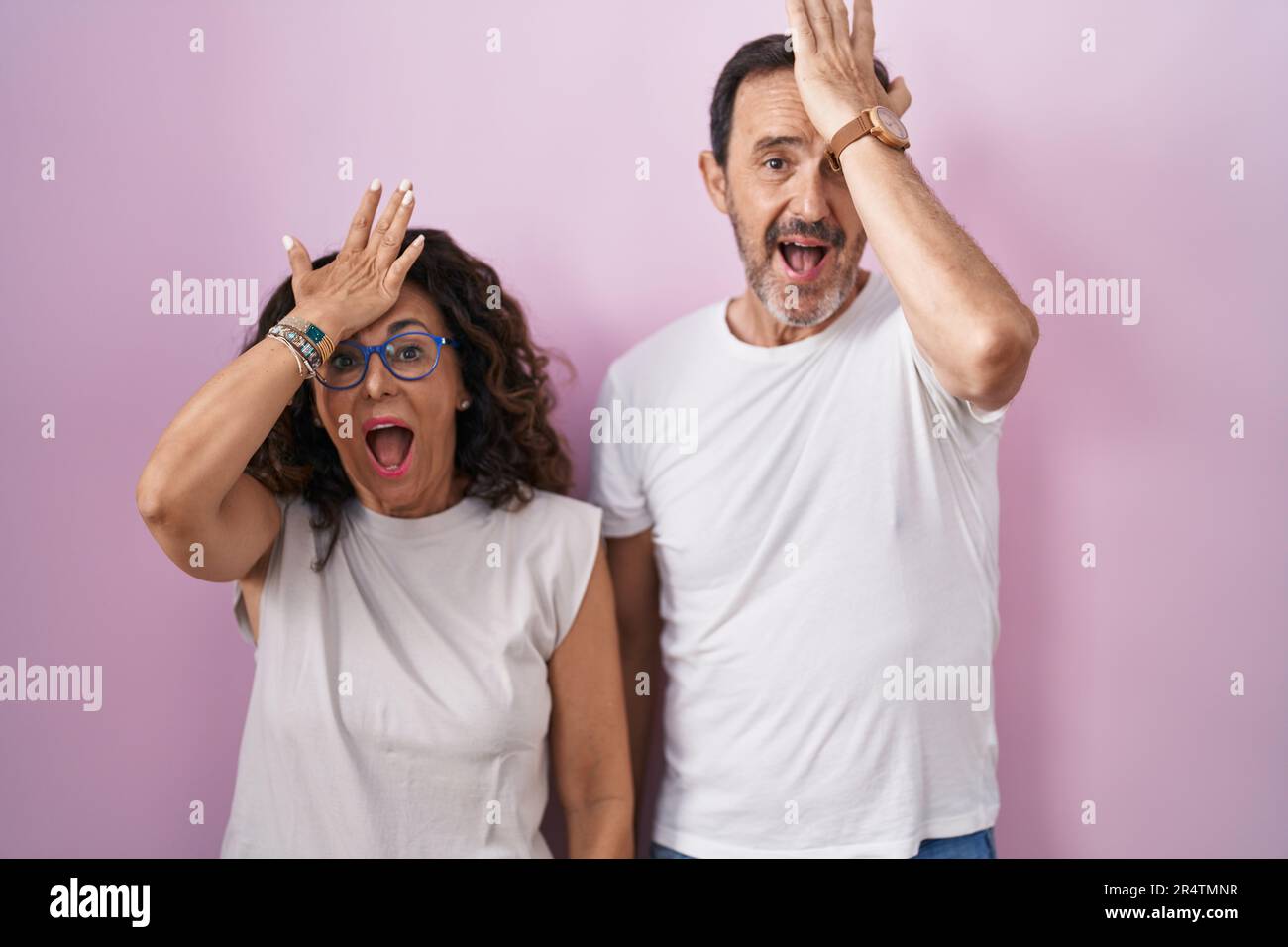 Couple hispanique d'âge moyen ensemble sur fond rose surpris par la main sur la tête pour l'erreur, rappelez-vous l'erreur. oubli, mauvais concept de mémoire. Banque D'Images Couple hispanique d'âge moyen ensemble sur fond rose surpris par la main sur la tête pour l'erreur, rappelez-vous l'erreur. oubli, mauvais concept de mémoire. Banque D'Images