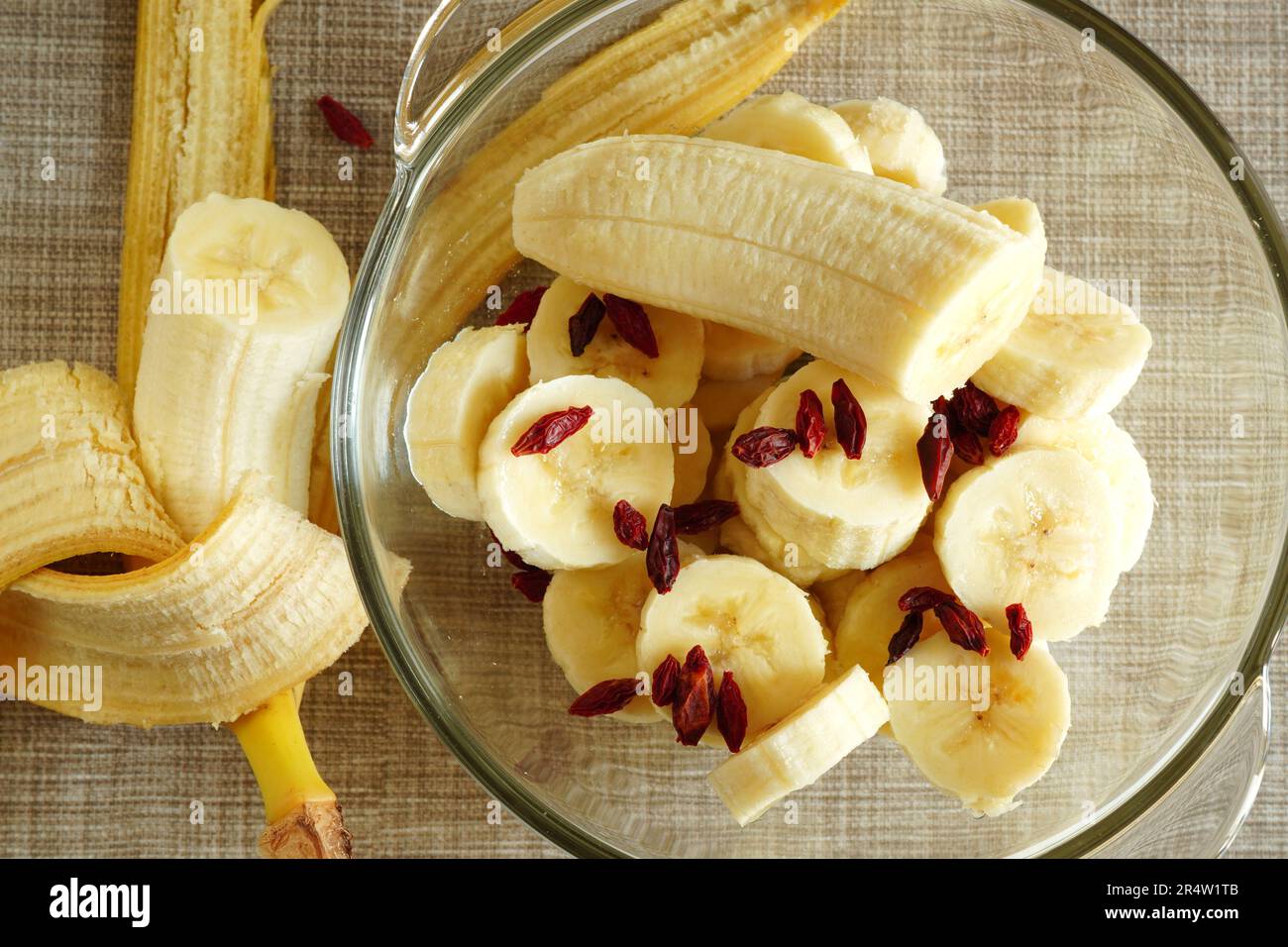 Tranches de bananes fraîches mûres et salade de fruits aux baies de goji dans un bol en verre Banque D'Images