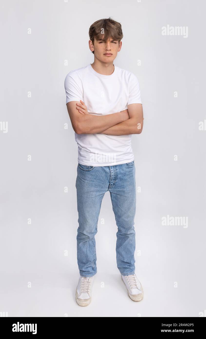 authentique hispanique adolescent garçon dans blanc T-shirt et bleu jeans,  en mettant le sien mains dans les poches, pensivement à la recherche une  façon 27051341 Photo de stock chez Vecteezy