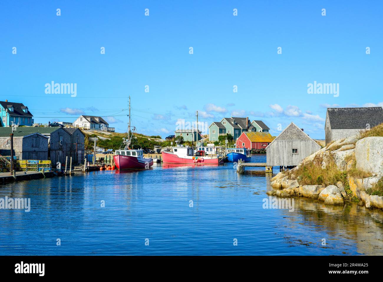 Un village de pêcheurs pittoresque au bord d'une côte rocheuse. Les bâtiments de stockage sont de couleur rouge, verte et bleue. Le ciel d'été est bleu foncé. Banque D'Images