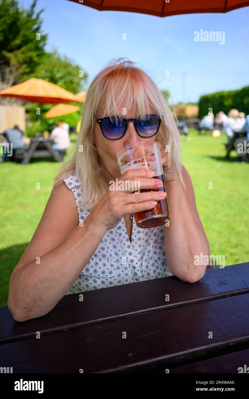 Femme buvant de la bière dans un jardin de pub Banque D'Images