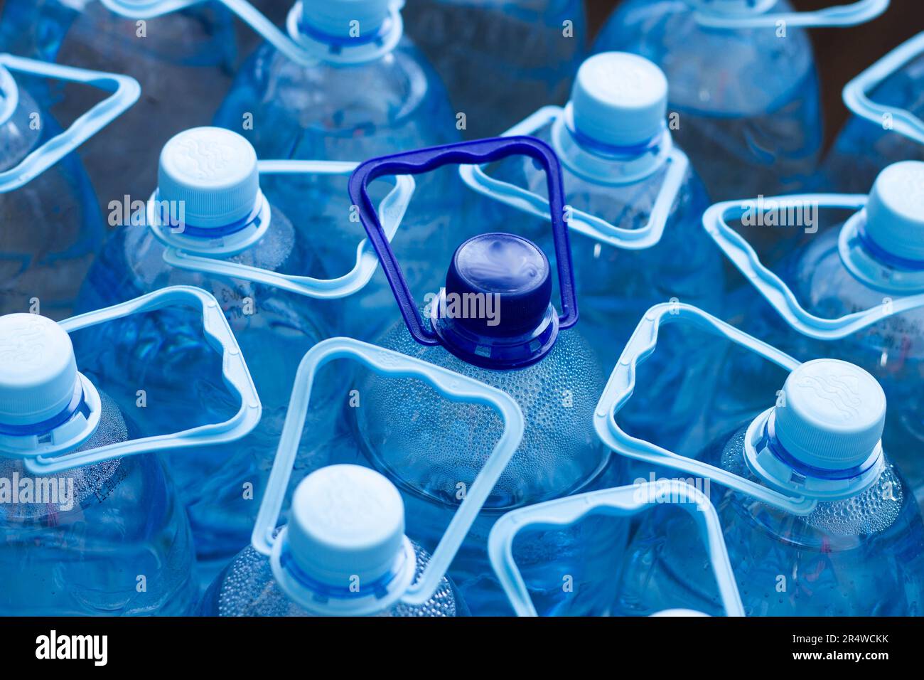 De nombreuses bouteilles en plastique bleu avec bouchons bleus et une avec bouchon bleu foncé avec eau minérale claire dans un supermarché. Eau pure, filtrée et écologique Banque D'Images