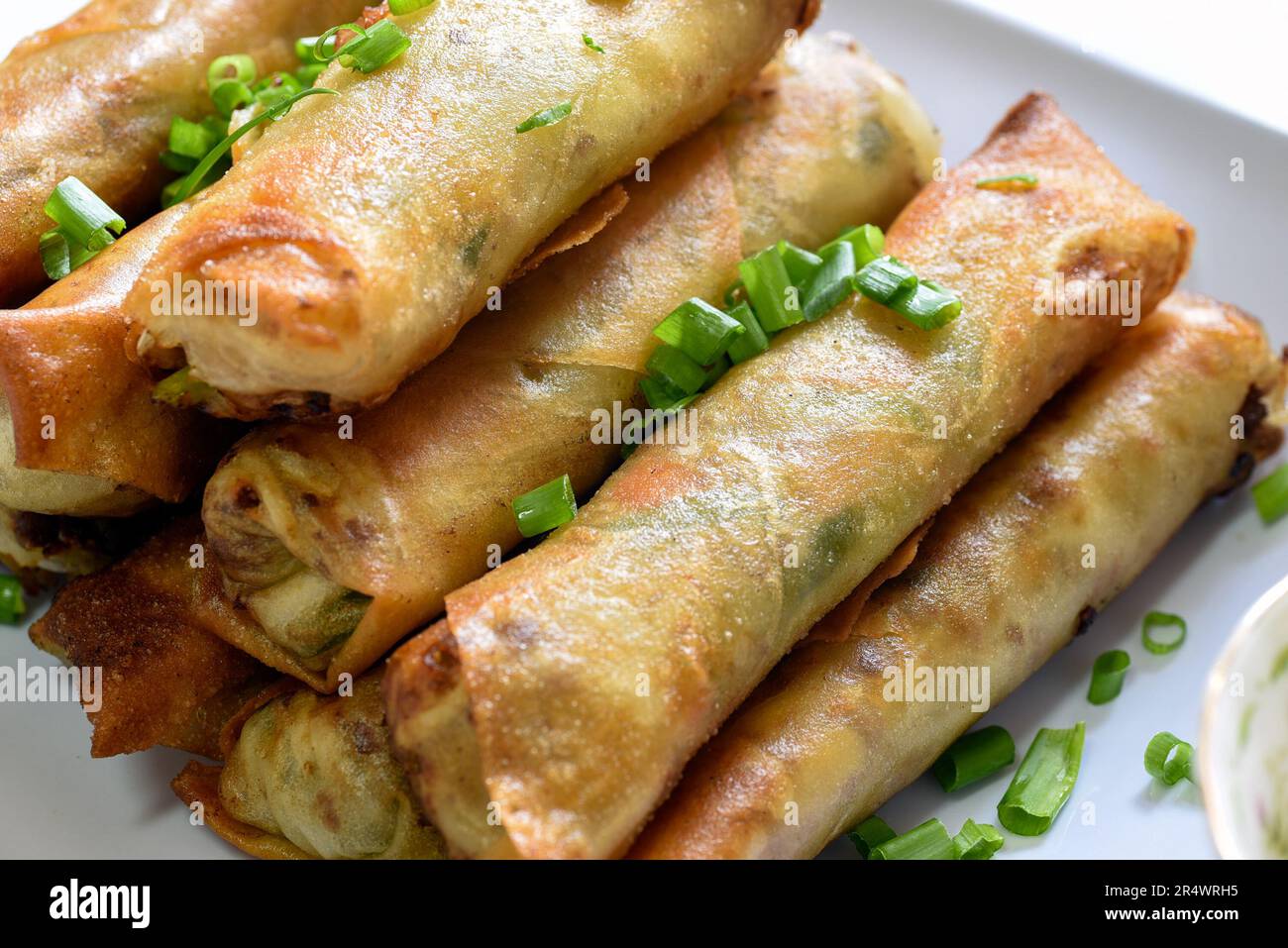 Lumpiang Shanghai avec des ciboules saupoudrées - une nourriture philippine. Banque D'Images