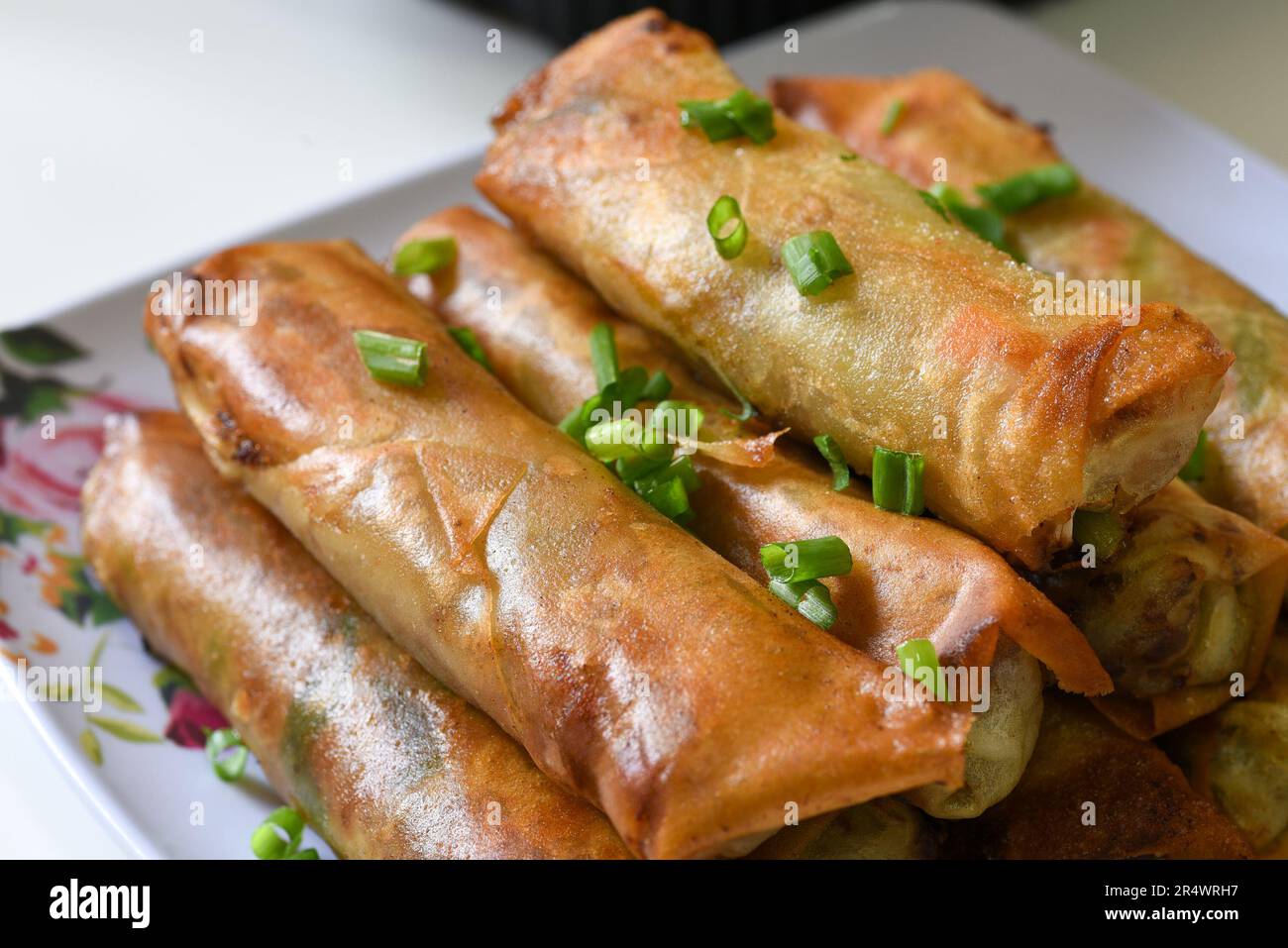 Lumpiang Shanghai avec des ciboules saupoudrées - une nourriture philippine. Banque D'Images