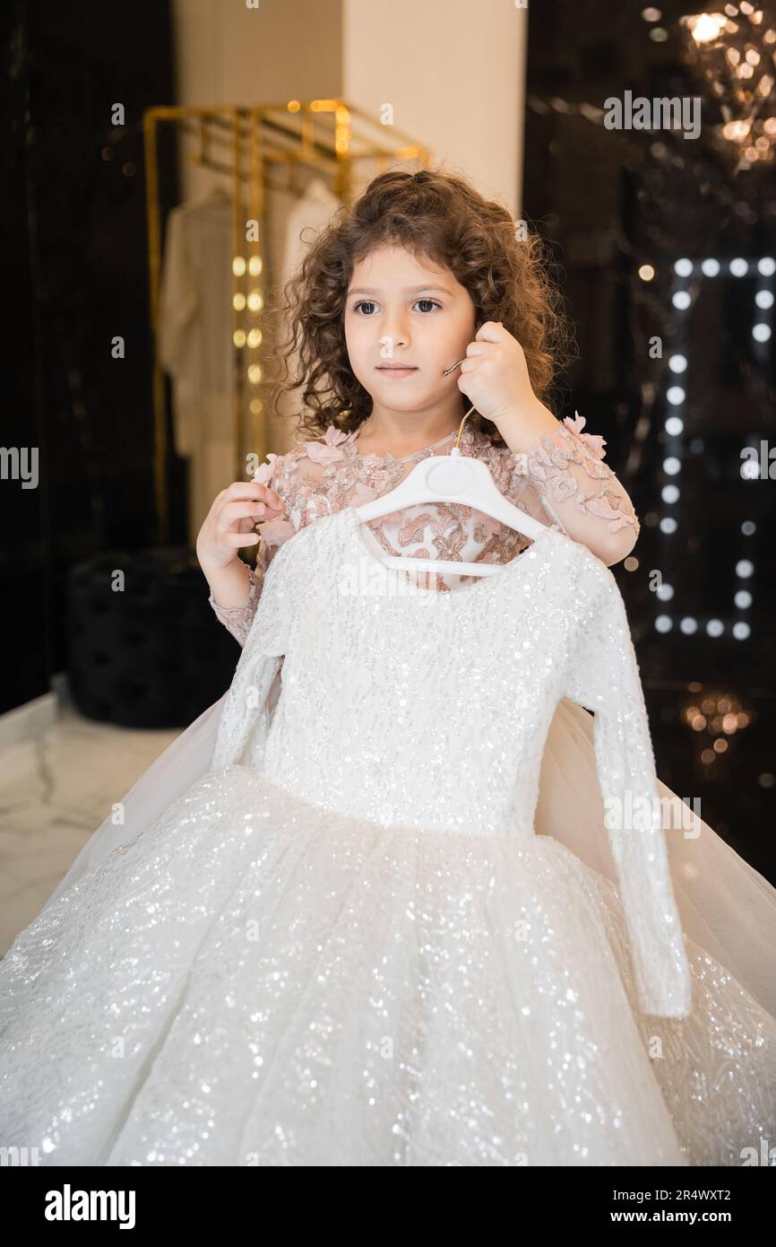 Petite fille tenant le cintre avec belle robe dans le vestiaire