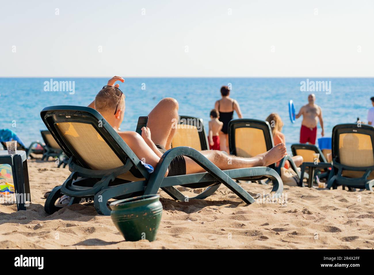 Antalya; Turquie-29 octobre; 2021: Un homme avec des lunettes de soleil couchée sur un lit de soleil et utilisant son téléphone mobile tout en prenant le soleil sur la plage. Antalya est populaire Banque D'Images