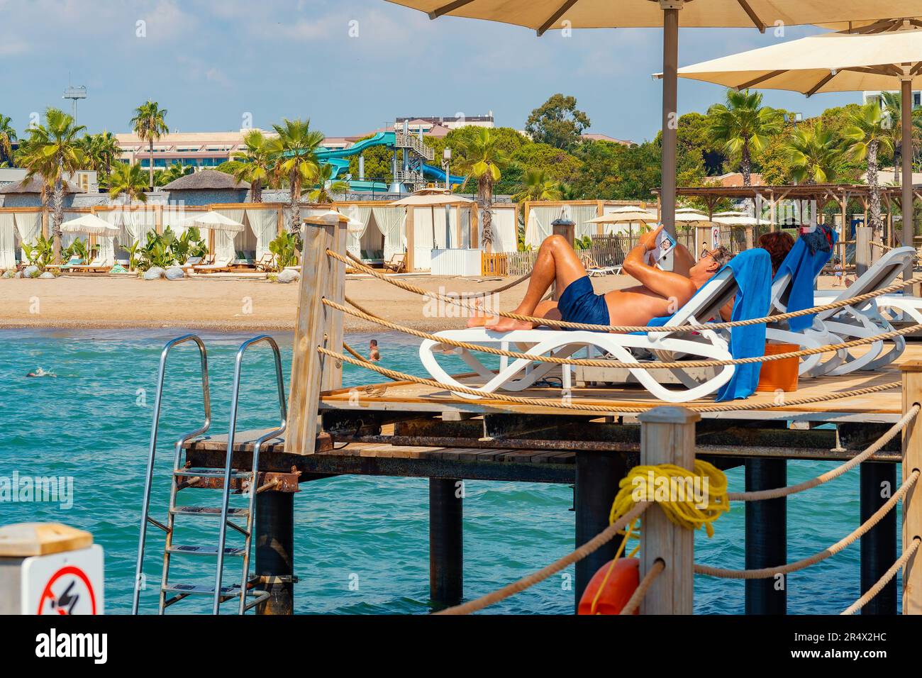 Antalya ; Turkey-11 septembre ; 2022 : personnes prenant un bain de soleil sur des chaises longues sous des parasols sur une jetée en bois en été. Antalya une ville populaire pour russe, Ukraine Banque D'Images