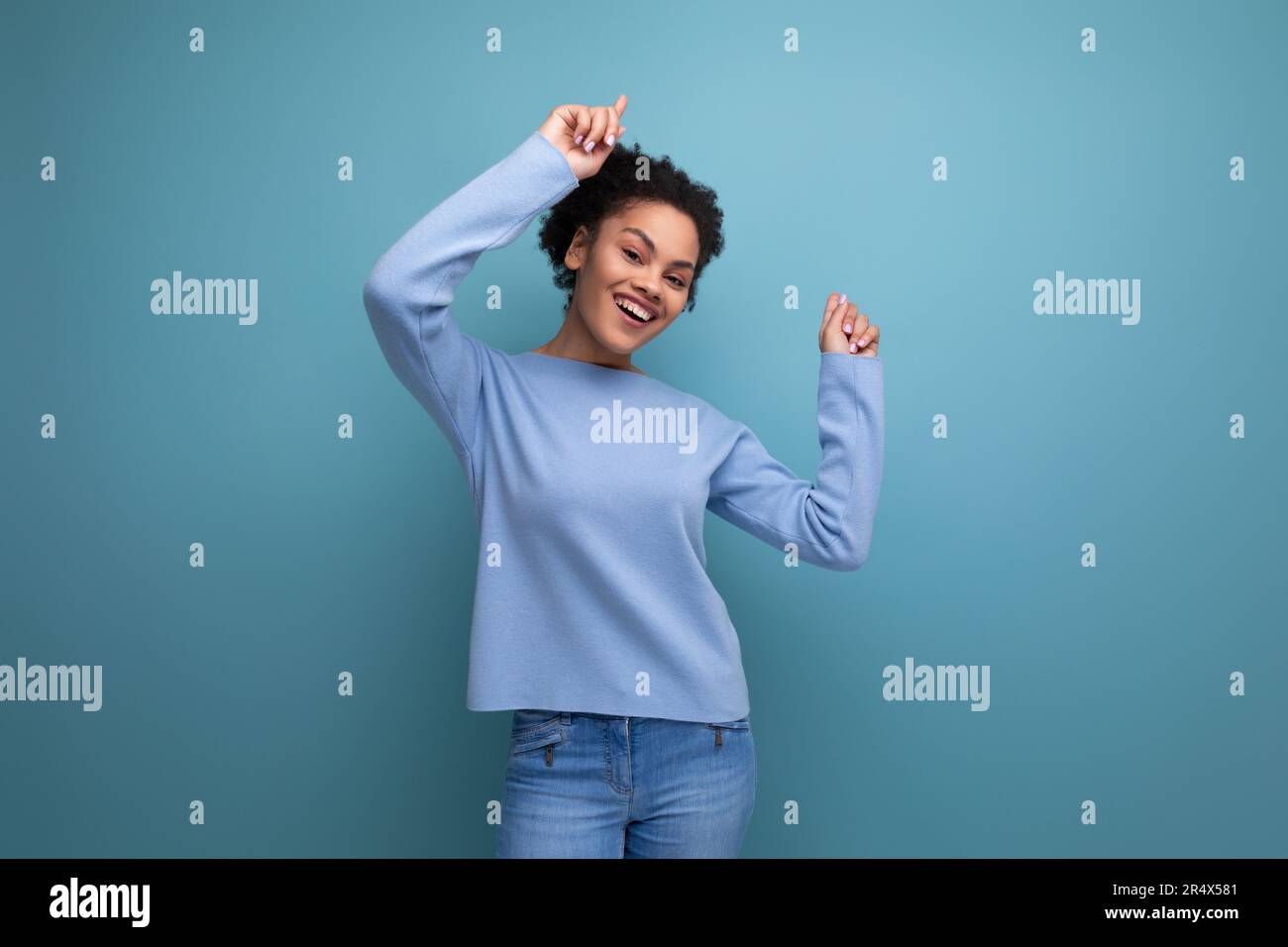 charmante femme brune souriante de 20s avec des boucles afro montrant de la joie Banque D'Images