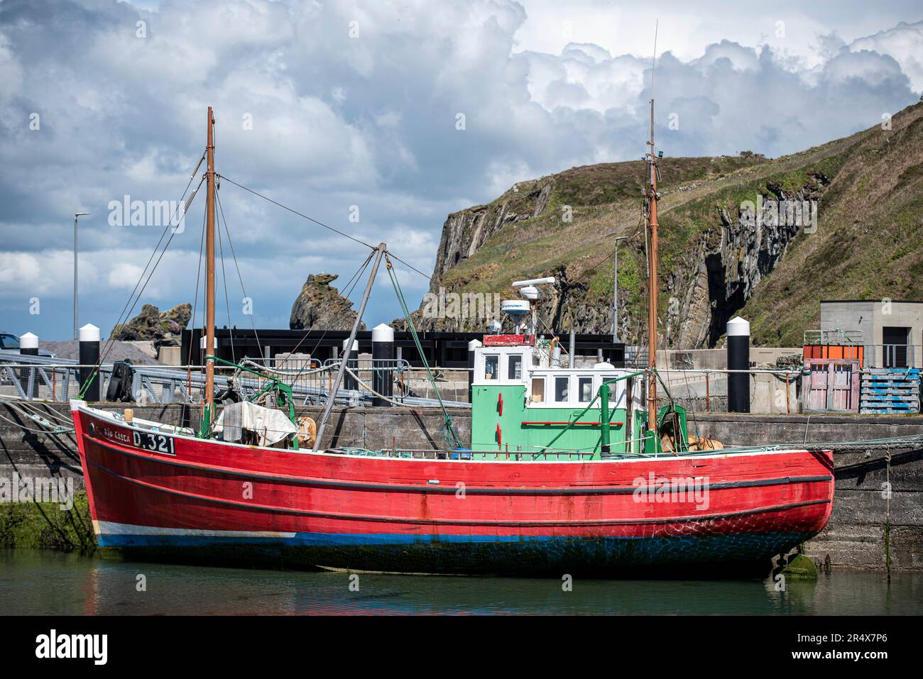 Vue rapprochée d'un bateau de pêche amarré dans le port de Sherkin Island avec les falaises de mer en arrière-plan ; West Cork, Irlande Banque D'Images