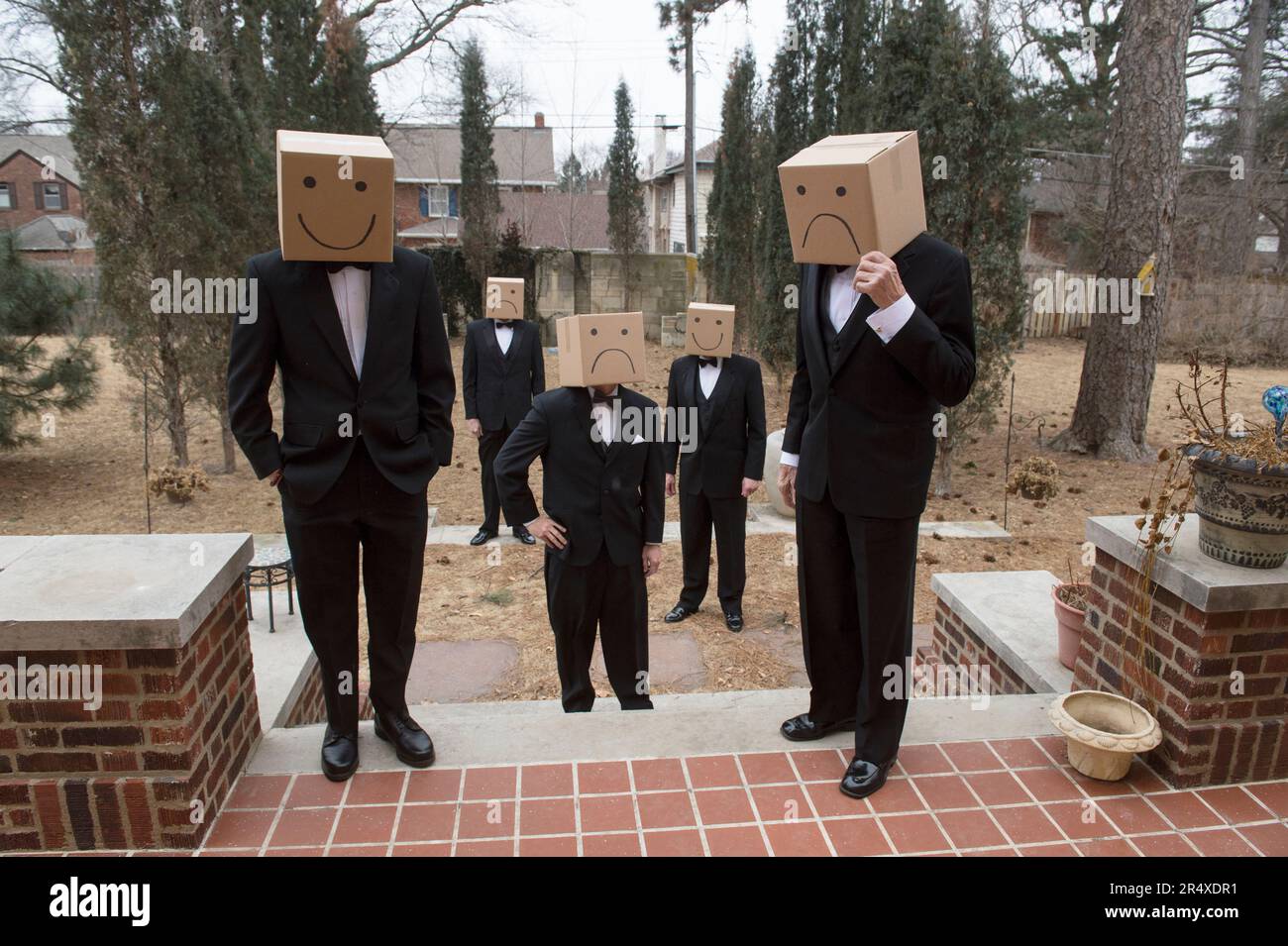 Cinq hommes à tête de boîte en tuxedos se trouvent dans un jardin résidentiel; Lincoln, Nebraska, États-Unis d'Amérique Banque D'Images