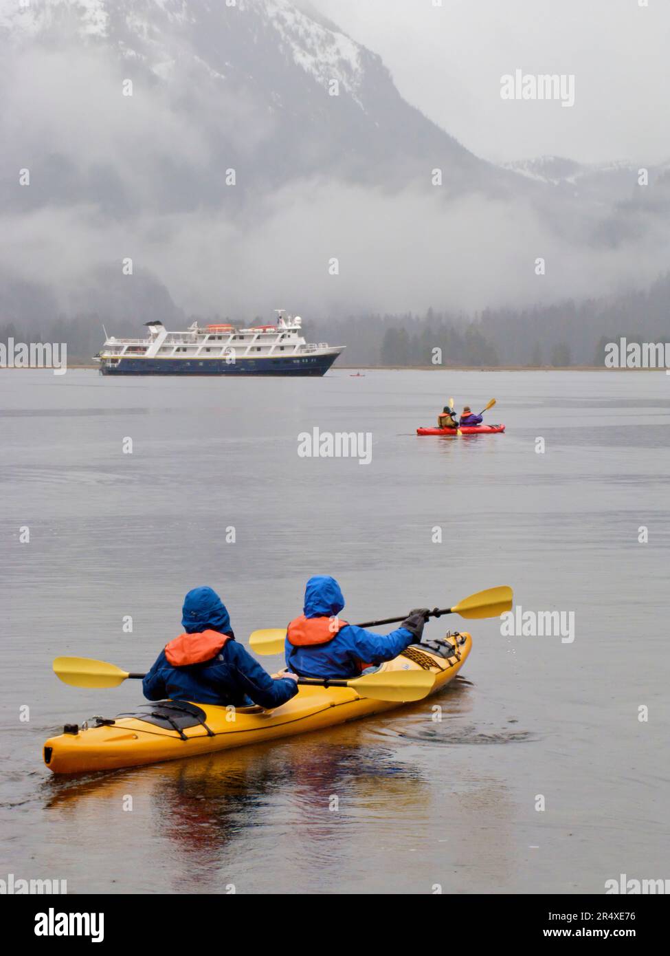 Kayak à Khutze Inlet près d'un bateau de croisière à Khutze Inlet, BC, Canada ; Colombie-Britannique, Canada Banque D'Images