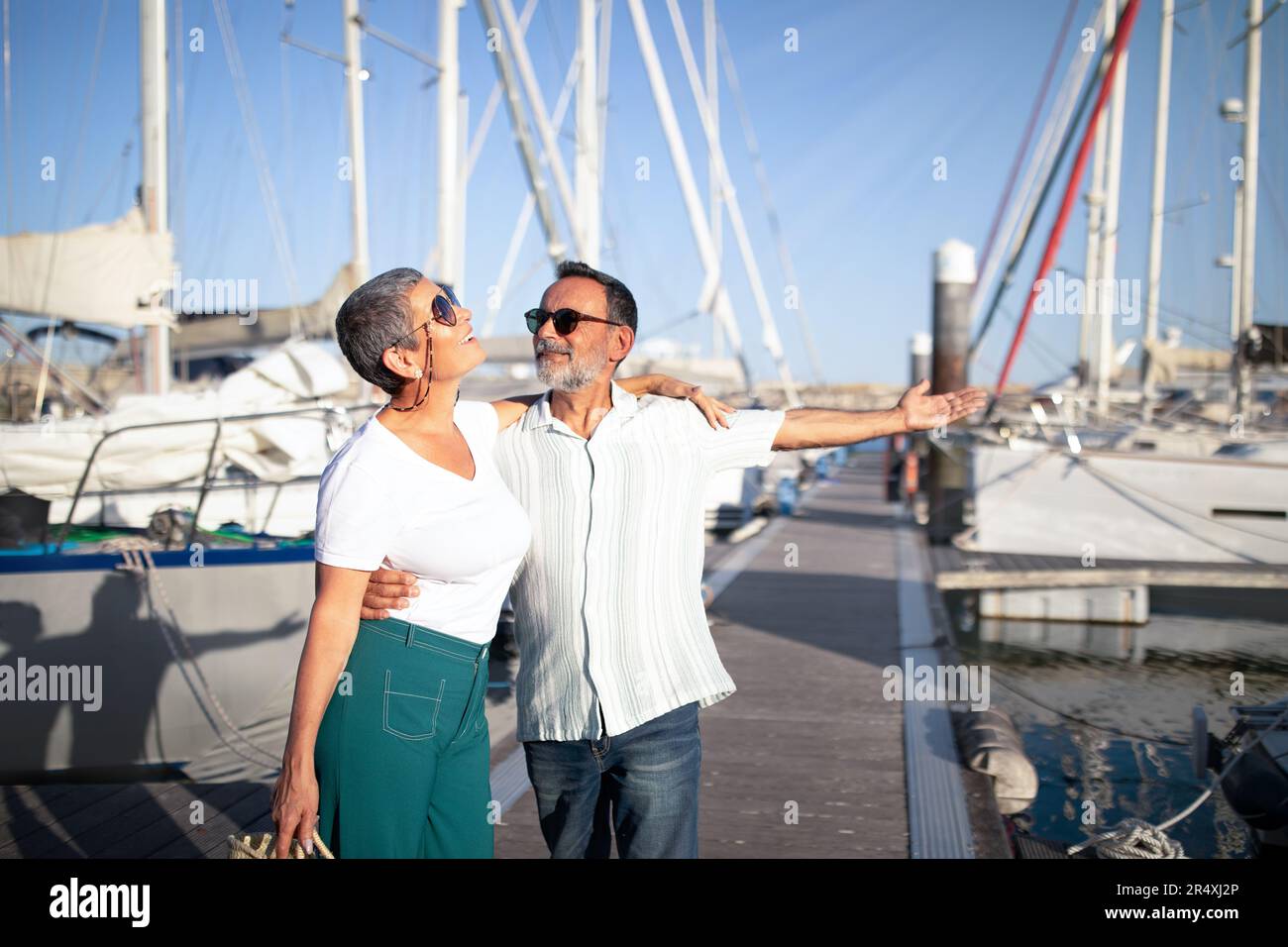 Un mari âgé embrassant sa femme montrant son nouveau yacht à Marina Banque D'Images