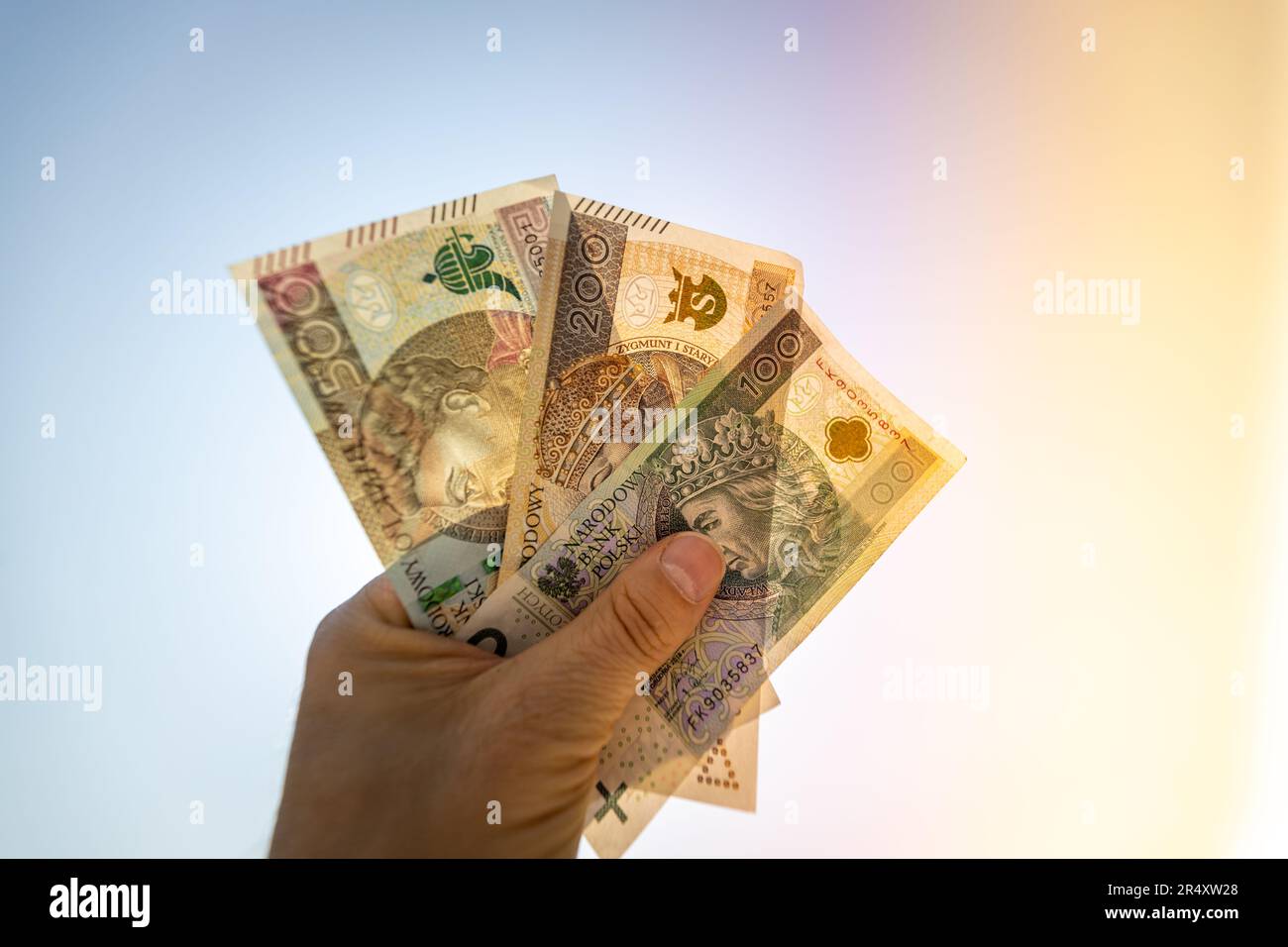 Pologne 800 plus, l'argent polonais dans un poing contre le ciel, photo rétroéclairé par le soleil, concept financier, programme social, prestations sociales Banque D'Images