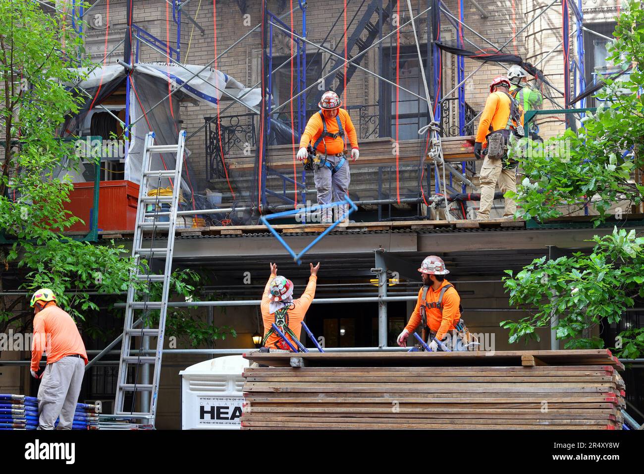 Des échafaudages, des ouvriers de construction déconstruisent des échafaudages et un abri de trottoir entourant un bâtiment en brique de maçonnerie à Manhattan, New York Banque D'Images