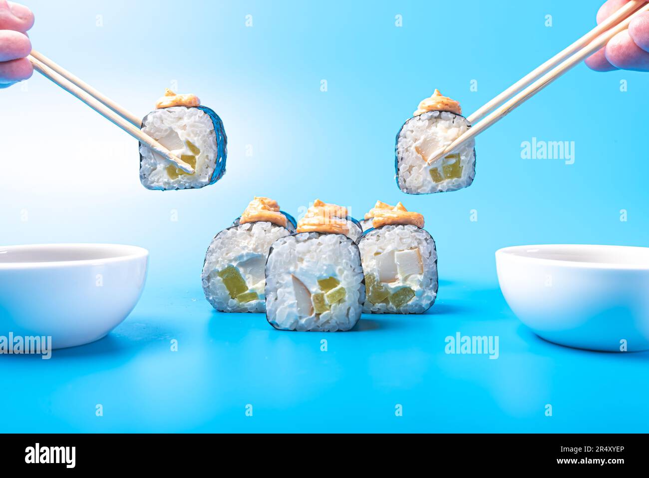 Morceaux de sushi roulés, avec fromage, daikon, poisson et sauce épicée, trempés dans de la sauce soja, sur fond bleu. Photo de haute qualité Banque D'Images