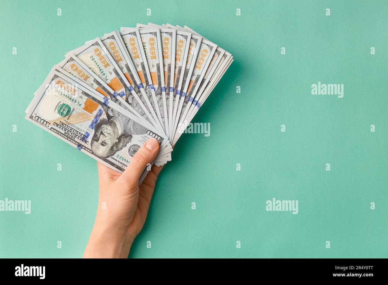 Beaucoup de billets de 100 dollars en mains sont pliés dans un ventilateur sur un fond vert vue de dessus avec de l'espace pour le texte. Monnaie, billets entre les mains des femmes. Banque D'Images