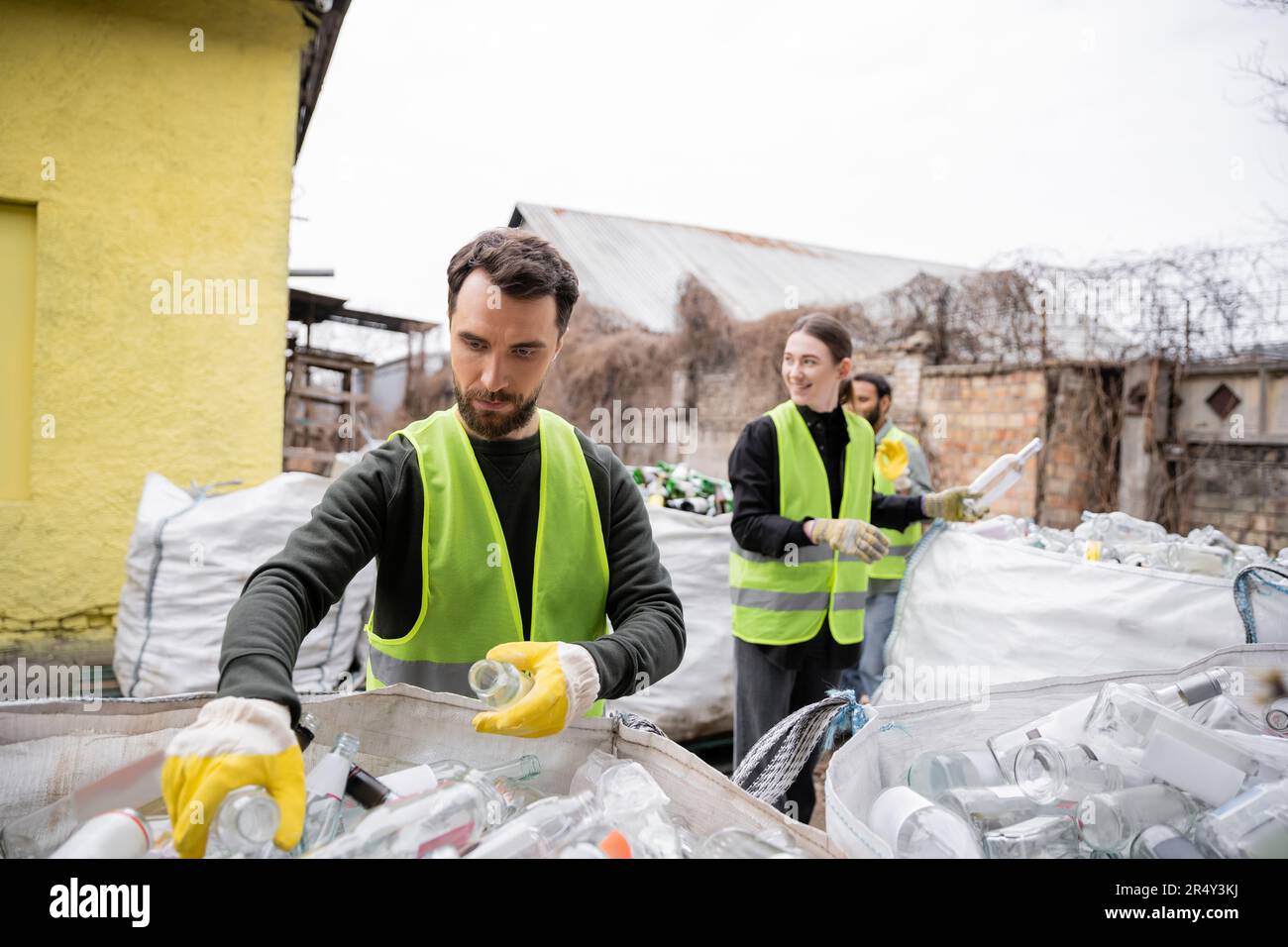 Trieur barbu dans un gilet haute visibilité et un gant de protection  séparant les ordures près du convoyeur et les collègues flous travaillant  ensemble dans l'élimination des déchets Photo Stock - Alamy