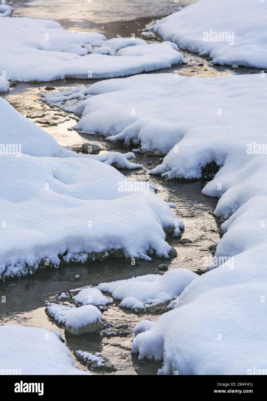 L'eau de la rivière coule près de pierres couvertes de glace et de neige, détail gros plan Banque D'Images