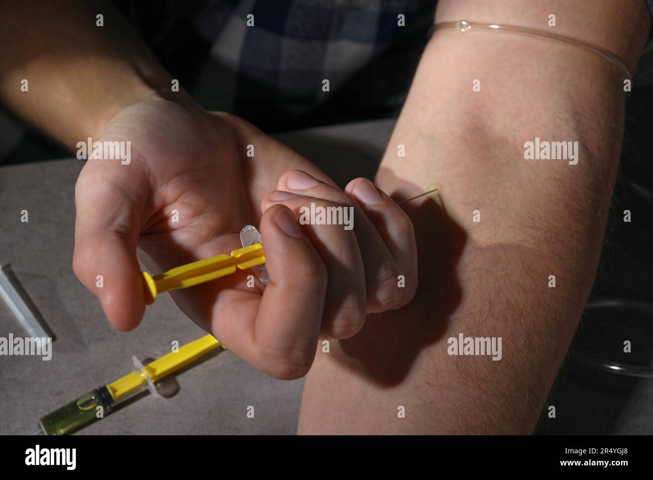 Homme accro prenant des médicaments à la table grise, gros plan Banque D'Images