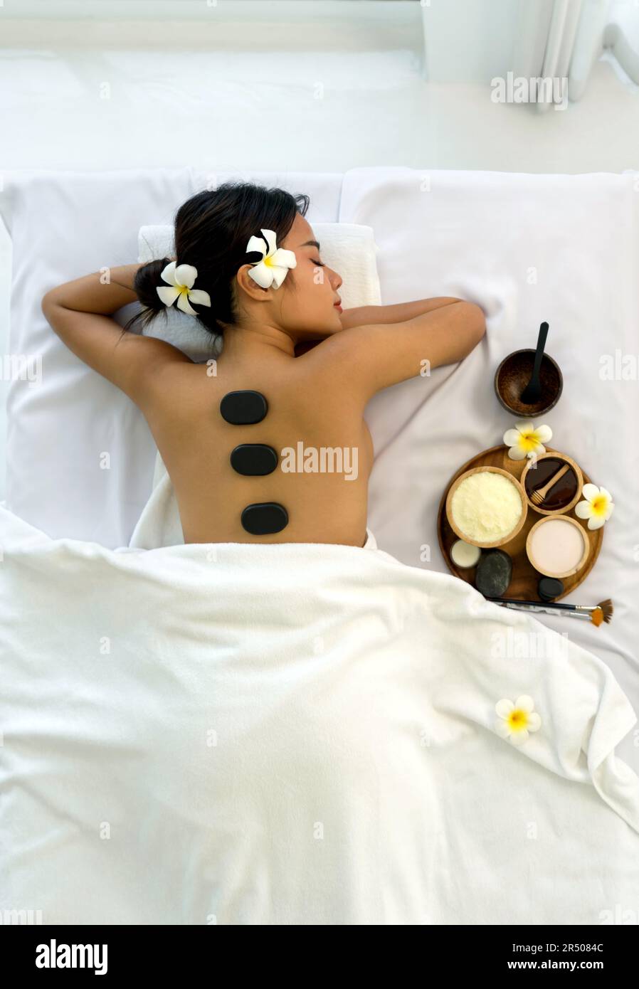 Femme recevant un massage spa aux pierres chaudes. Allongé sur une table de massage, relaxant avec les yeux fermés. Spa soins thermaux aromathérapie pour le corps de beauté. S Banque D'Images