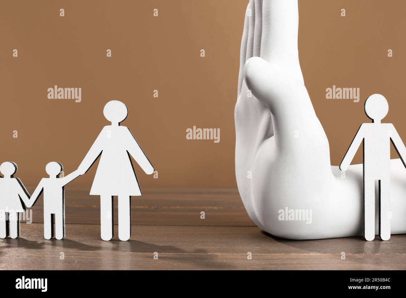 Concept de divorce. Modèle à la main en papier divisant des figures de femme avec des enfants et d'homme sur une table en bois Banque D'Images