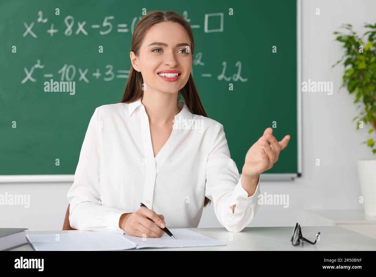 Un jeune professeur de mathématiques donne une leçon à table en classe Banque D'Images