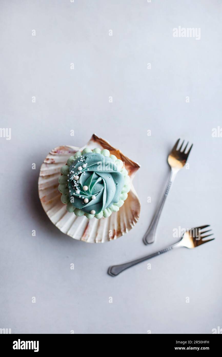 Gâteau monoportion avec glaçage bleu dans une coquille de palourdes Banque D'Images