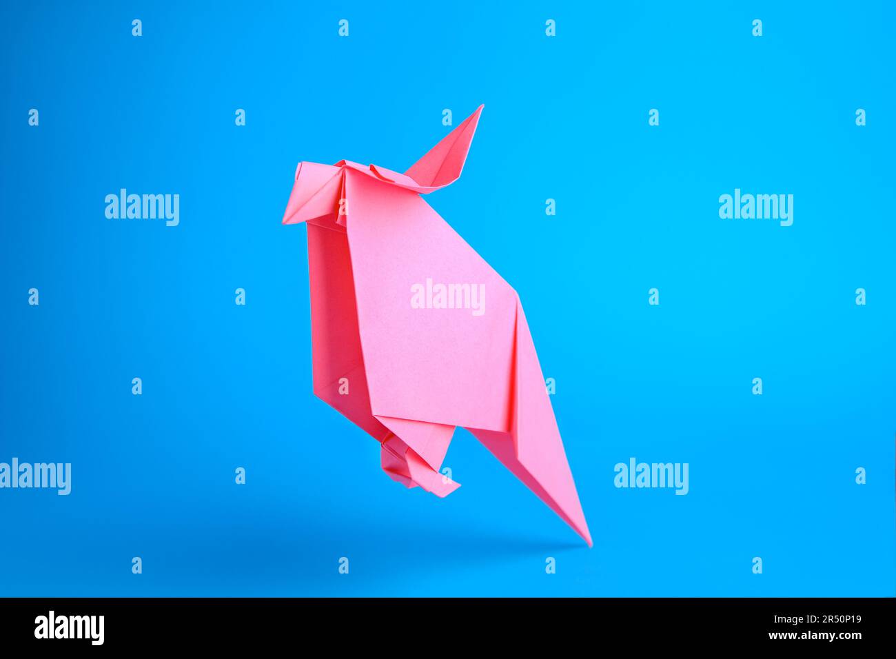 Art origami Perroquet en papier rose fait à la main sur fond bleu clair Banque D'Images