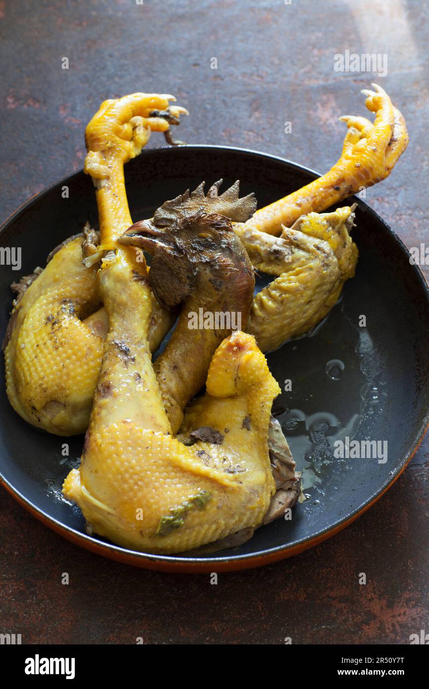 Poulet avec tête et pieds dans une casserole Banque D'Images