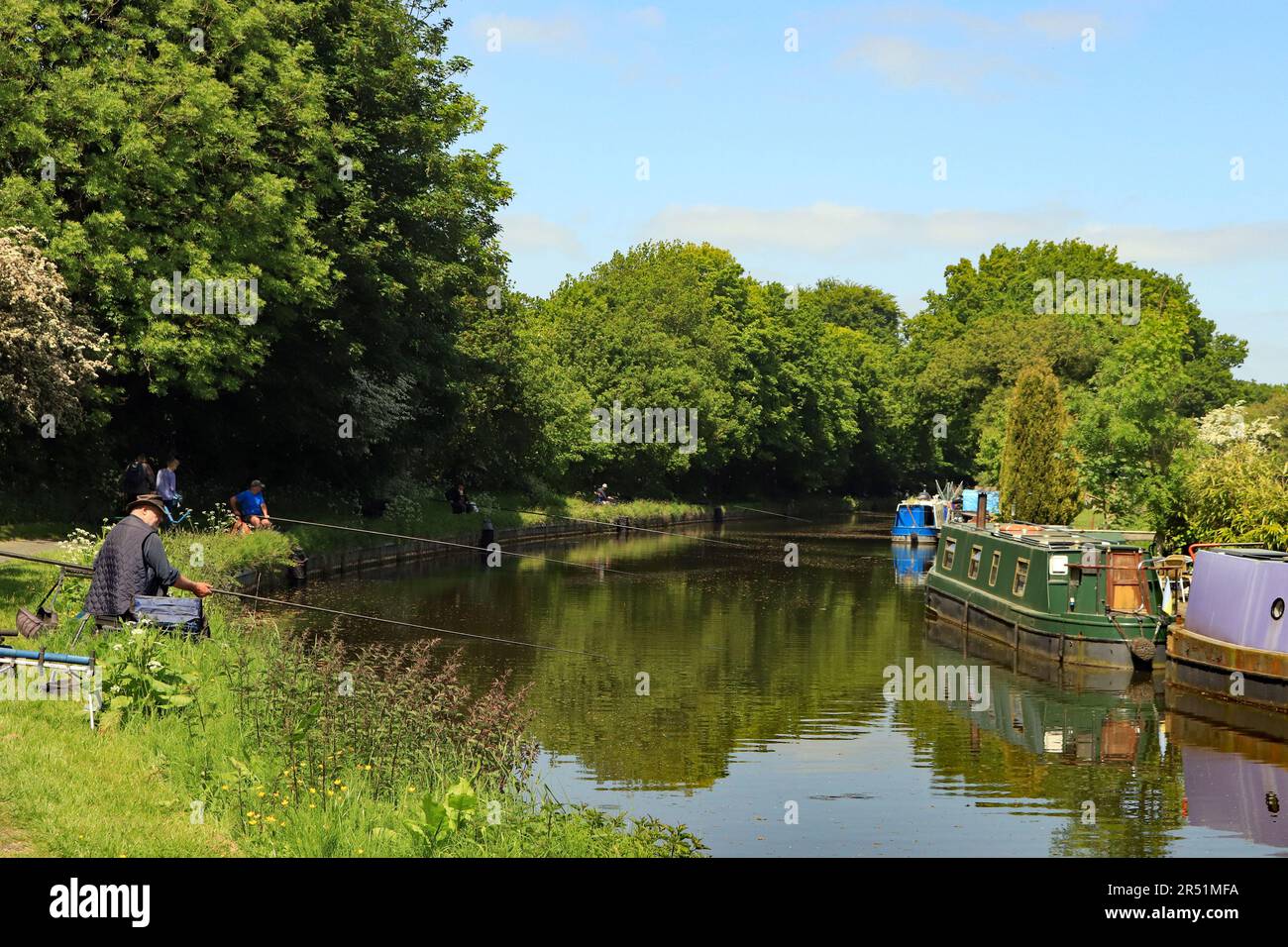 Au cours d'un après-midi de printemps chaud, les longs pôles sont sortis, presque jusqu'aux bateaux amarrés, lors d'un match de pêche sur le canal de Leeds et Liverpool dans le Lancashire Banque D'Images