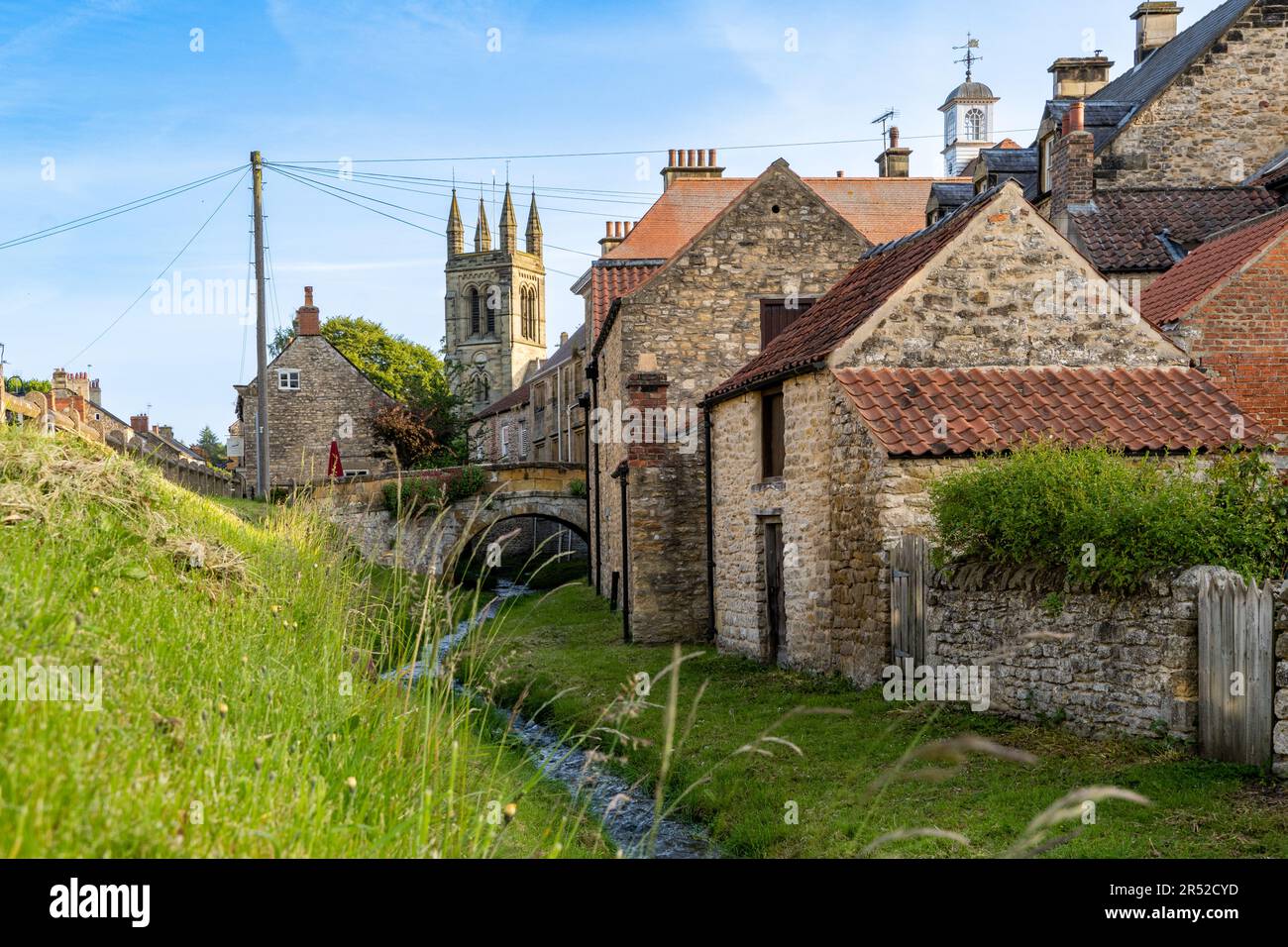 HELMSLEY, NORTH YORKSHIRE, ROYAUME-UNI - 29 MAI 2023. Bâtiments traditionnels en pierre et petit ruisseau de village traversant la destination touristique populaire de Banque D'Images
