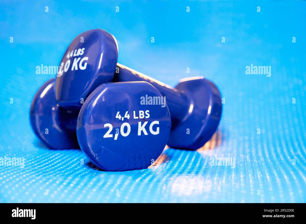 Petits haltères en vinyle bleu utilisés pour le yoga, les pilates et d'autres sports sur un tapis Banque D'Images
