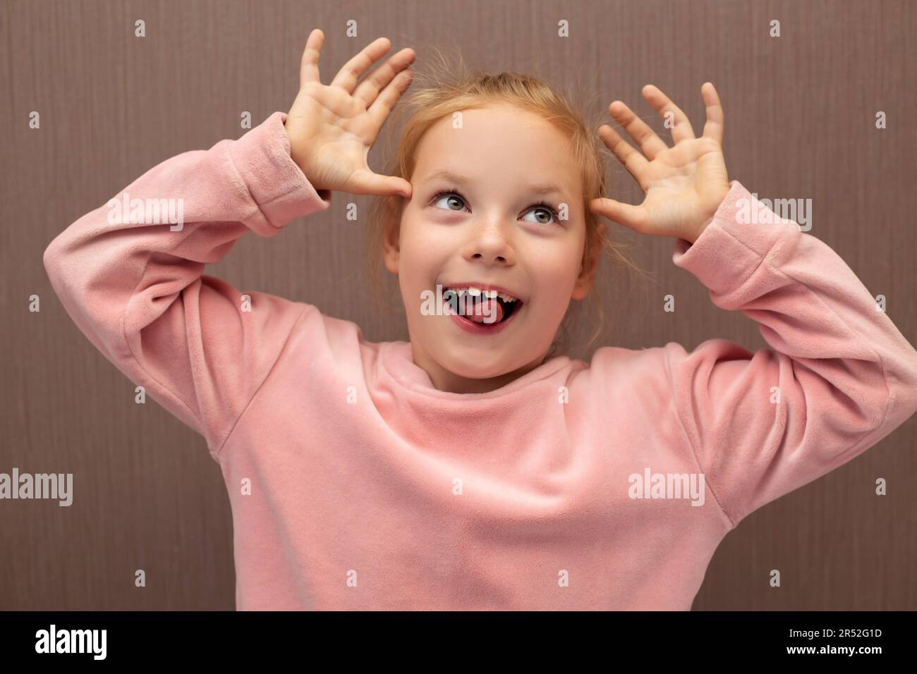 Fille d'enfant étant impoli et faisant des visages drôles avec sa langue et les mains. Banque D'Images