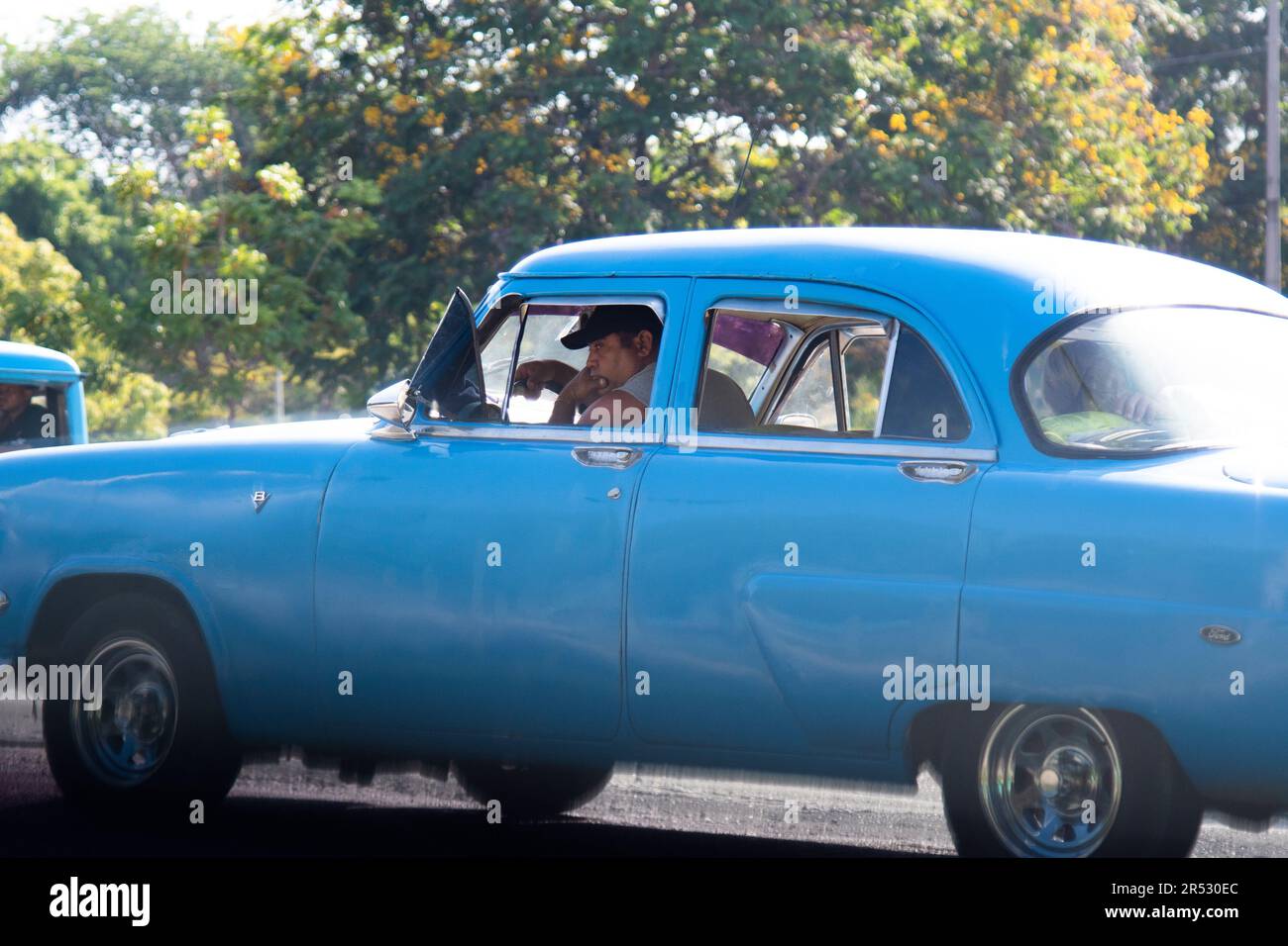 L'homme cubain est assis dans sa vieille voiture à un feu à la Havane, Cuba. Banque D'Images