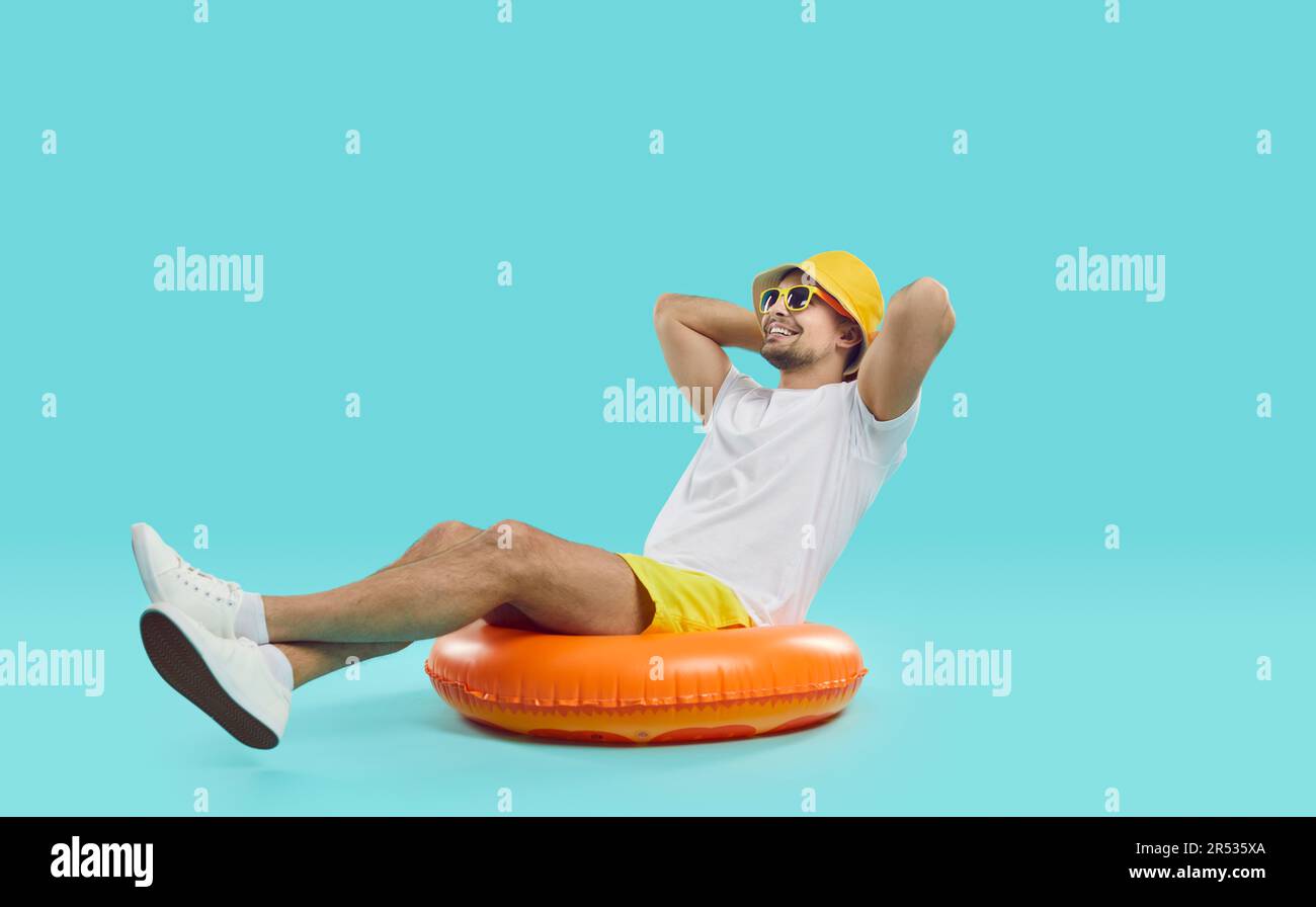 Heureux satisfait jeune homme aime les vacances d'été en mer assis sur un cercle gonflable de natation. Banque D'Images