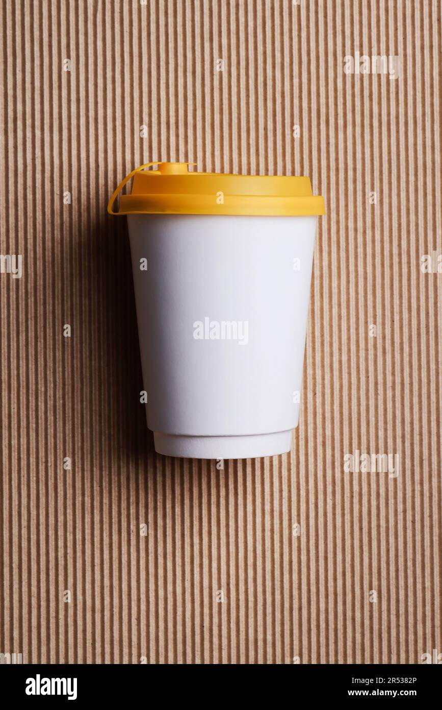 Blanc blanc blanc papier à emporter gobelet de recyclage avec couvercle jaune sur fond marron nervuré , maquette , modèle, espace pour votre texte , publicité. Banque D'Images