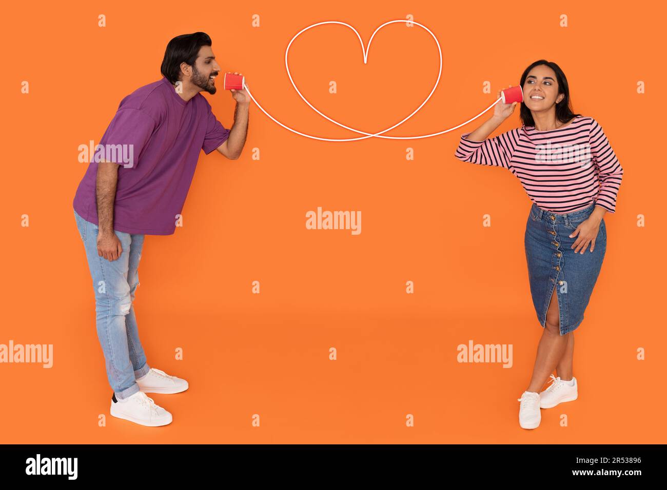Jeune couple indien avec téléphone CAN sur fond orange Banque D'Images