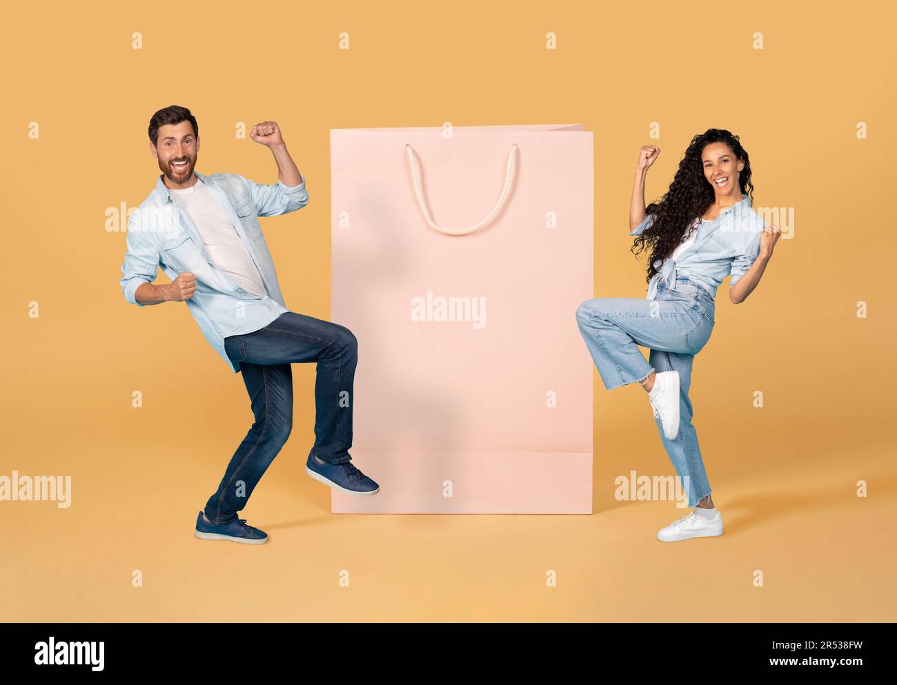 Un jeune couple heureux qui se présente à côté d'un énorme sac de shopping Banque D'Images