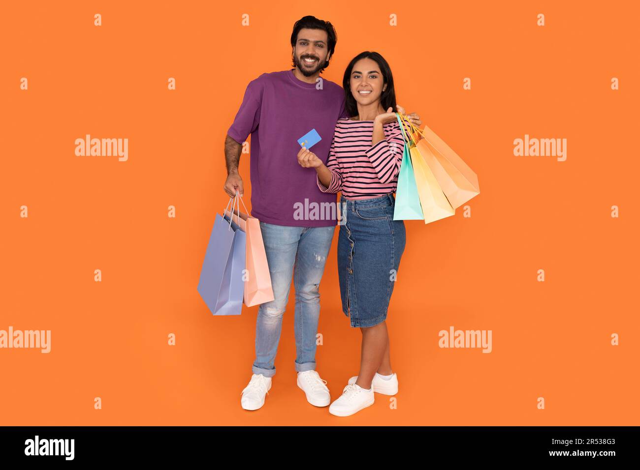 Les amoureux indiens heureux tenant des sacs d'achats et une carte bancaire Banque D'Images