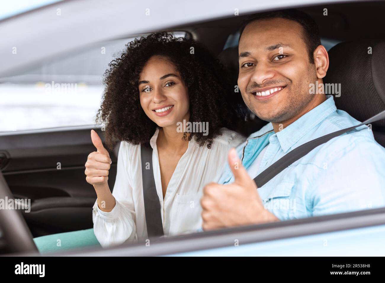 Couple arabe souriant qui fait des gestes avec les Thumbs Up assis en mode Auto Banque D'Images