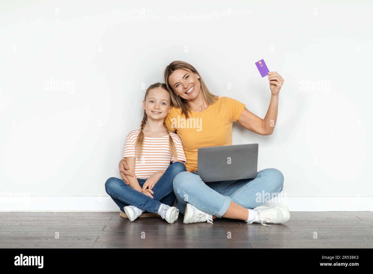 Paiements faciles. Jolie petite fille et mère tenant un ordinateur portable et une carte de crédit Banque D'Images
