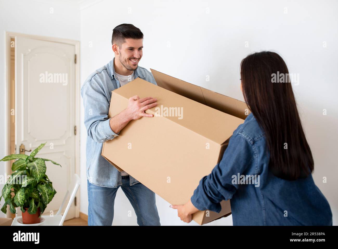 Joyeux couple européen portant une grande boîte en carton avec des Bellongings à la maison Banque D'Images